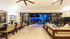 A spacious living area with a dining table, sofas, and a TV.