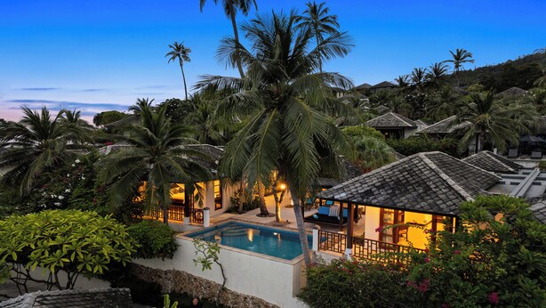 A resort with a swimming pool, palm trees, and traditional architecture.