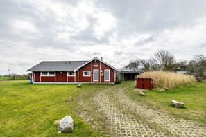 A red building with a paved driveway and a small shed. - Holiday Home 'Haus Albertsen' with Private Terrace, Private Garden and Wi-Fi (Hellschen-Heringsand-Unterschaar)