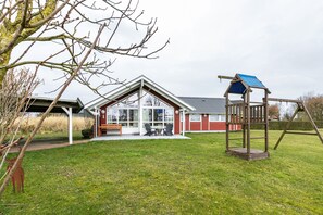 Une maison avec un patio couvert, une balançoire et une pelouse.