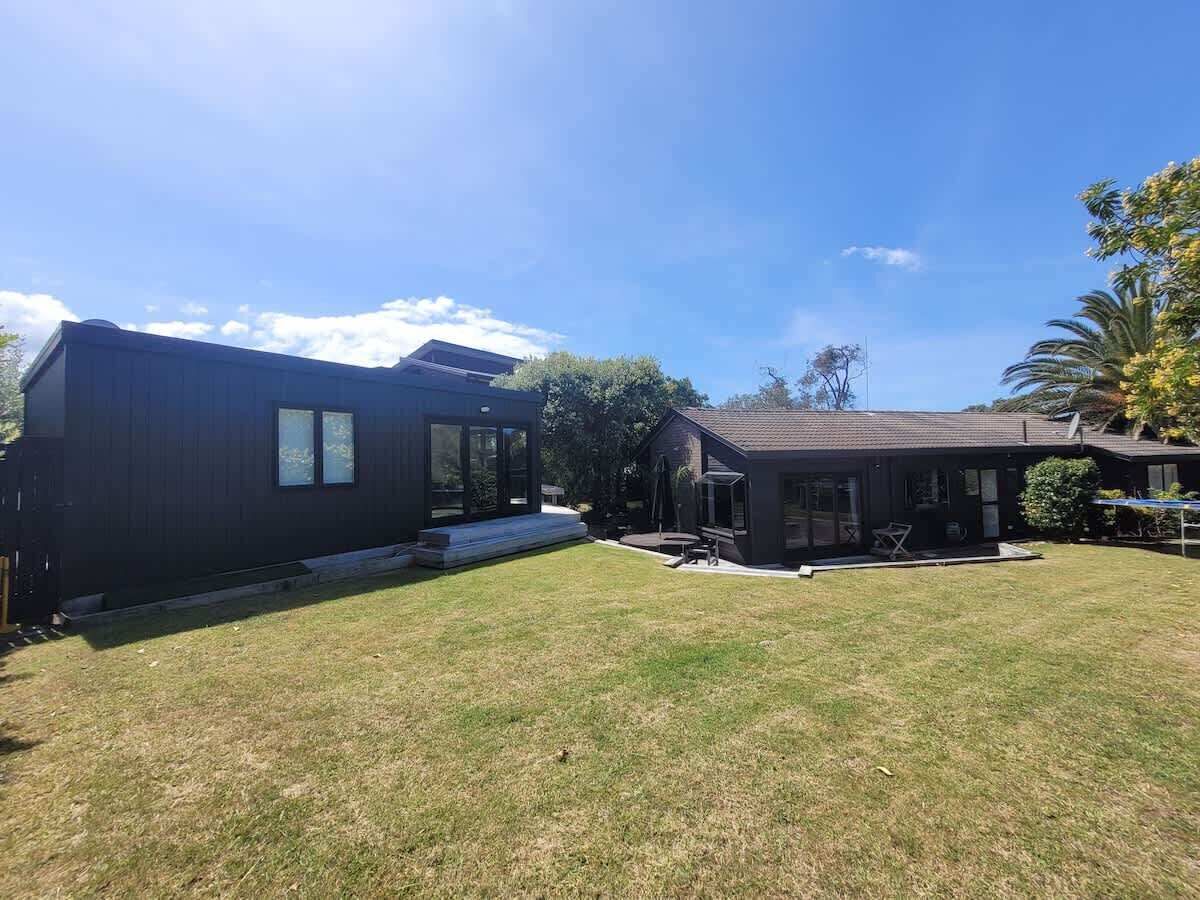 Una moderna casa a due piani con un ampio giardino, un patio e una piscina.