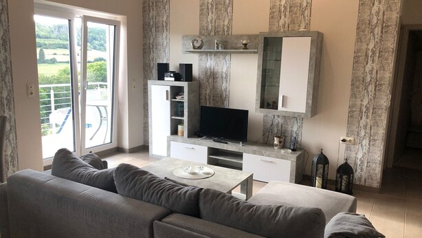 Un salón con sofá, televisión y balcón con vistas.