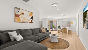 A modern living room with a grey sofa, a round coffee table, and a large abstract painting on the wall.