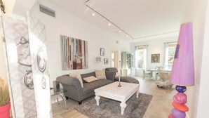 Una sala moderna con un sofá gris, una mesa de centro blanca y una lámpara colorida.