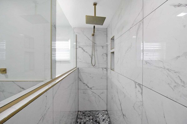 A modern bathroom with marble walls and a shower area. - Chic & modern canal-front retreat with private pool - Azure Tides (Punta Gorda)