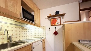 A compact kitchen with wooden cabinets, a stainless steel sink, a microwave, and a dishwasher.