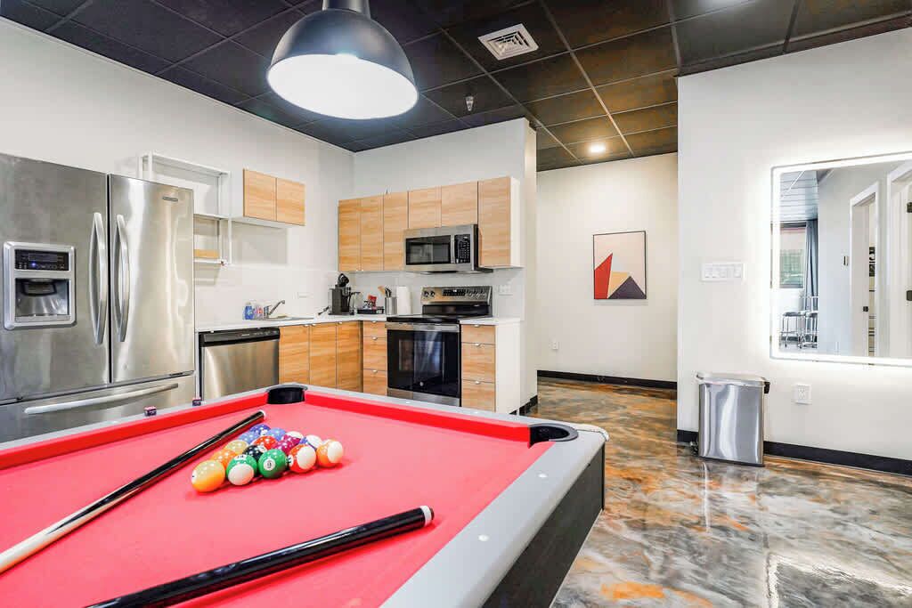 A modern kitchen with stainless steel appliances, a pool table, and a marble floor.