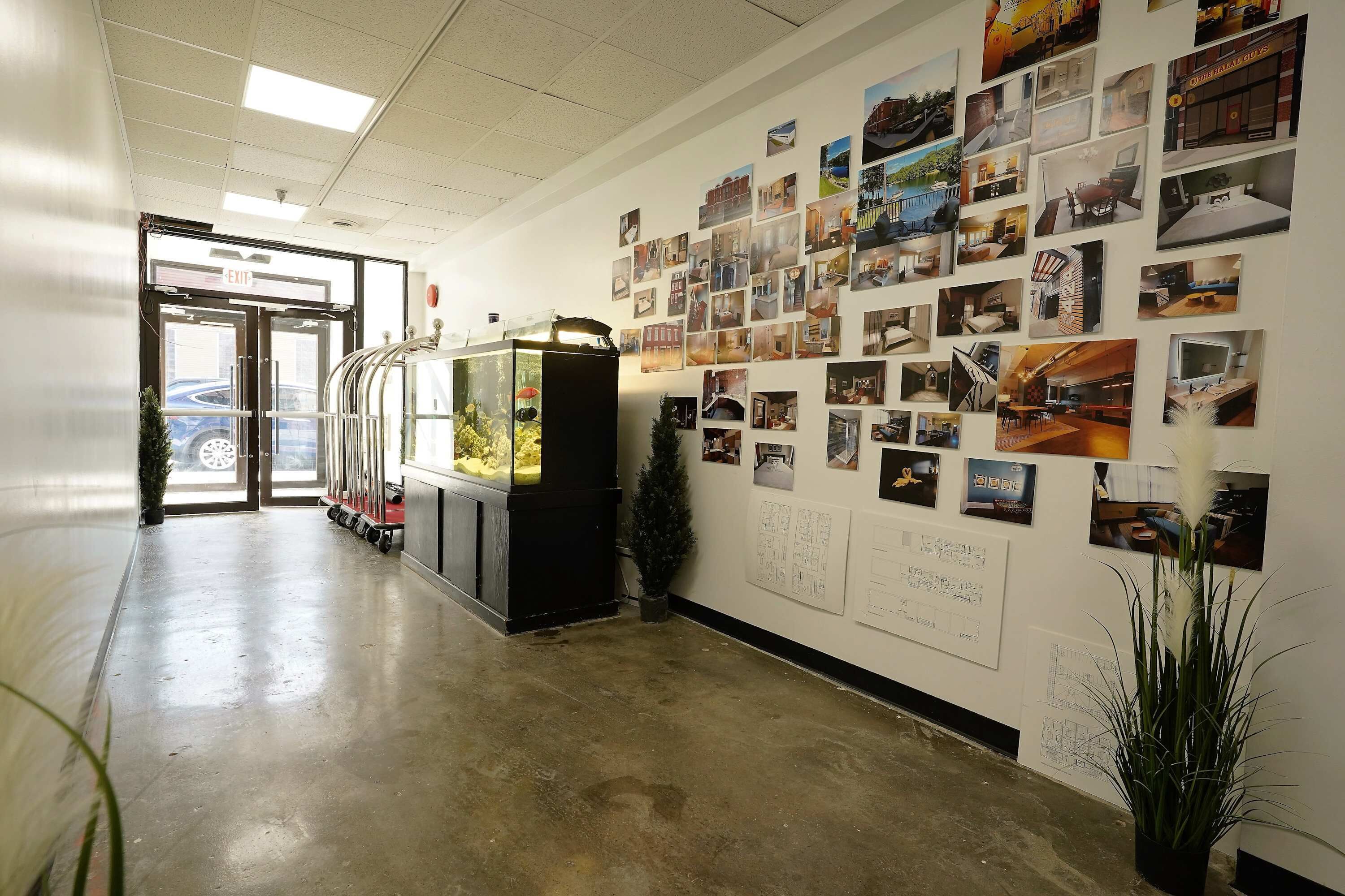 A hallway with a wall of photographs, a vending machine, and a potted plant.