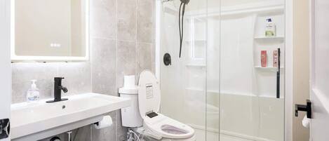 Une salle de bain moderne équipée de toilettes, d’un lavabo et d’une douche à parois en verre.