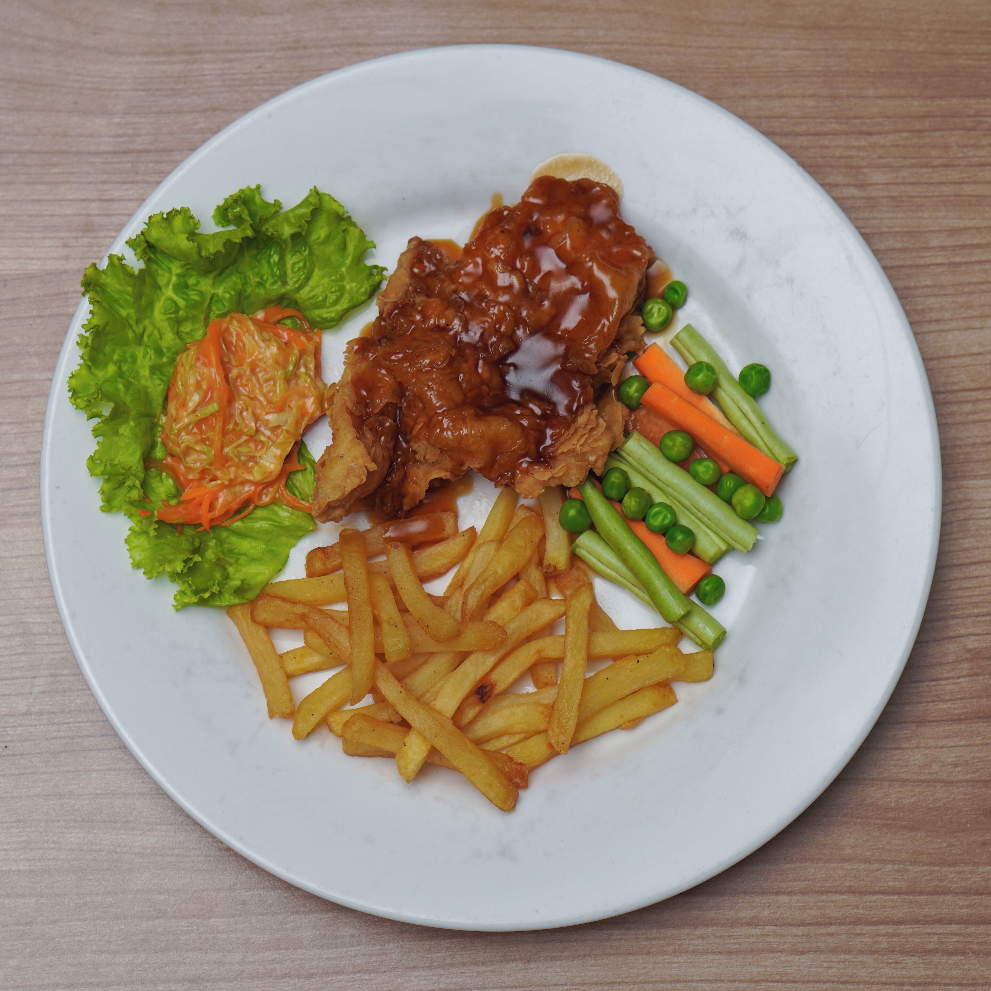 A plate with a meat dish, fries, and vegetables.