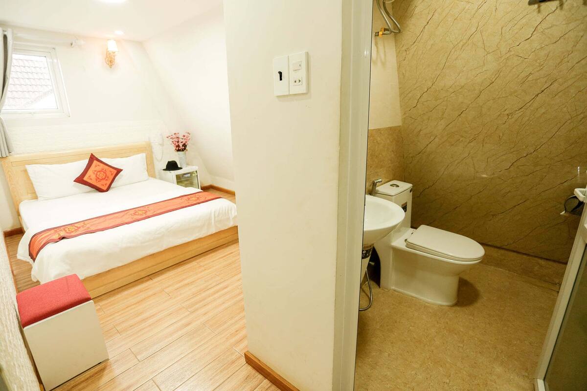 Une chambre d’hôtel comprenant un lit, une table de chevet et une salle de bain avec des toilettes et une douche.