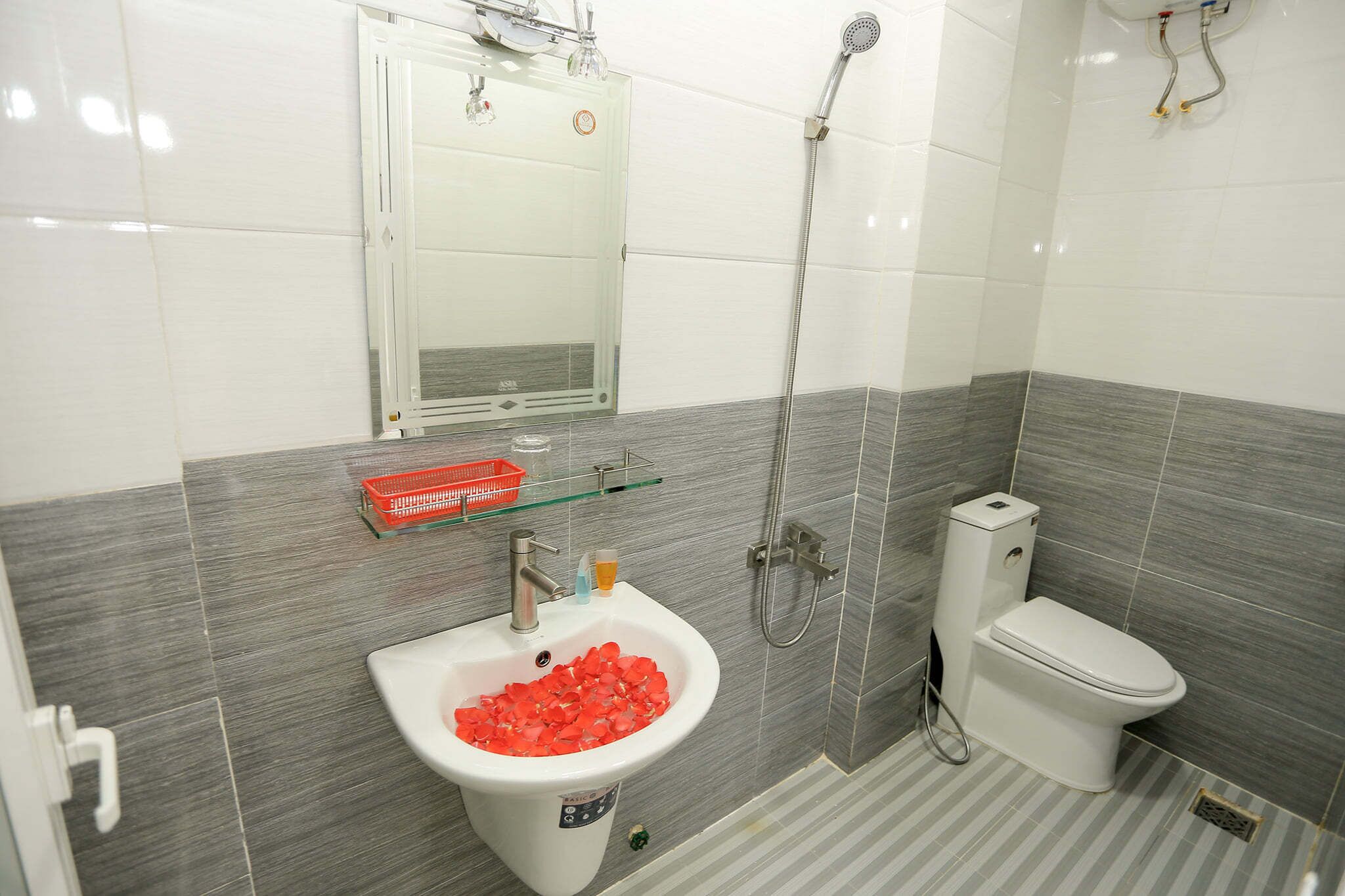 A bathroom with a white sink, a glass shelf, a toilet, and a shower.