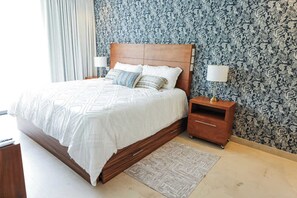 Cozy retreat with a large bed, wooden nightstand, and decorative wallpaper.