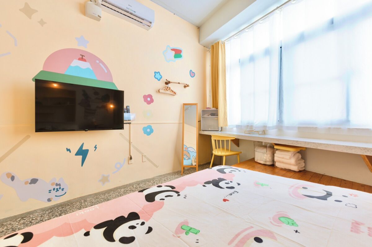 A child-friendly room with a TV, a desk, and a window.