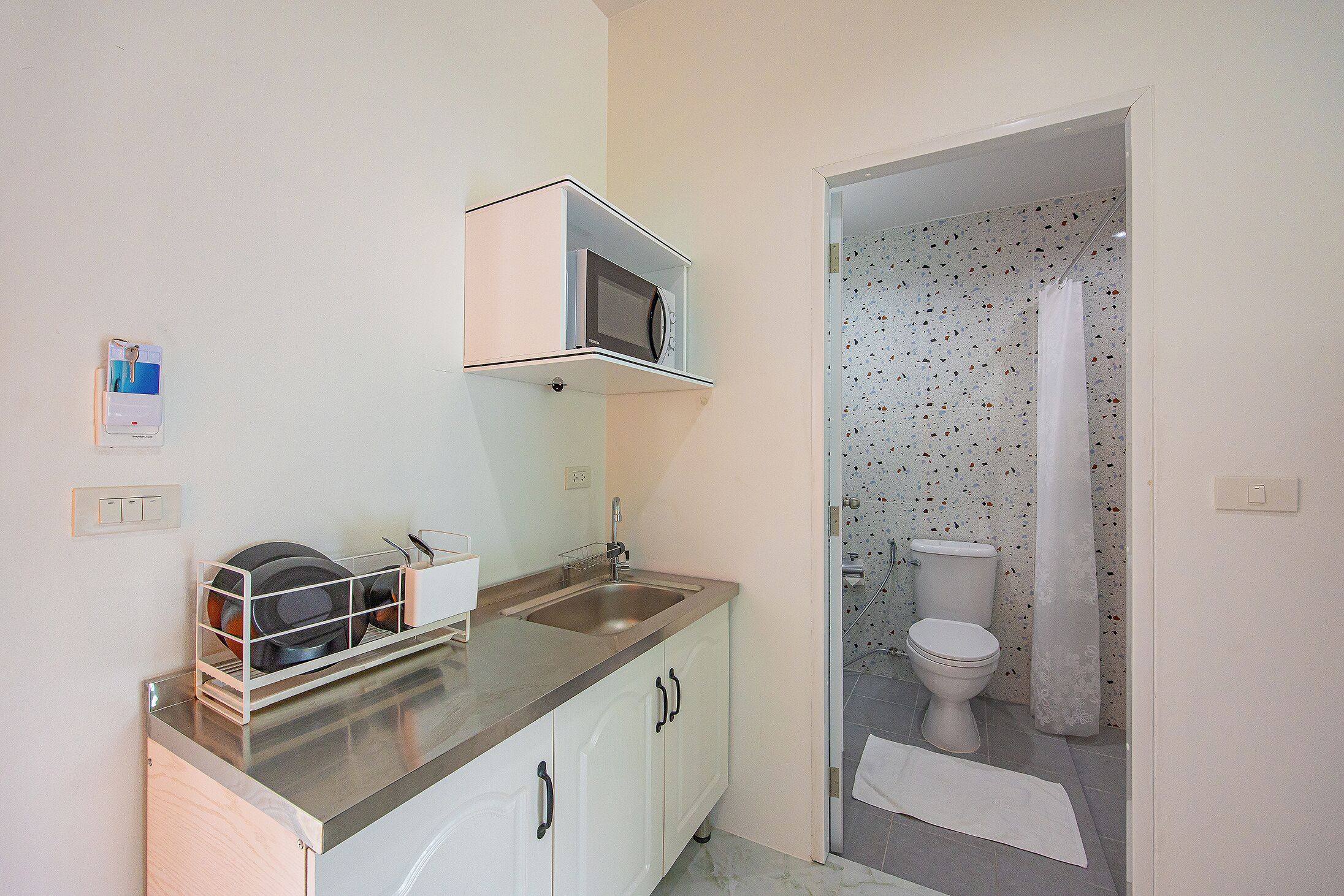 A compact bathroom with a shower, toilet, and a sink with a dish rack.