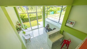 A bright room with a large window, a desk, two chairs, and a small cabinet. - Karon Hotel  at 22 (Karon)