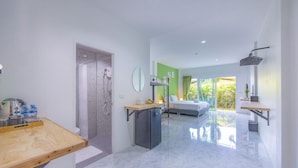 A modern hotel room with a marble floor, a wooden desk, a bed, a small refrigerator, and a balcony with a view of greenery. - Karon Hotel  at 22 (Karon)