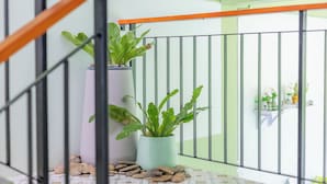 A balcony with a metal railing, potted plants, and a tiled floor. - Karon Hotel  at 22 (Karon)