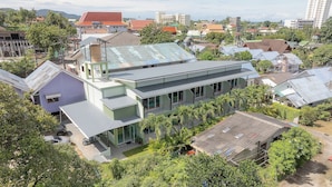 A modern building with a flat roof, multiple balconies, and a mix of residential and commercial structures in the background. - Karon Hotel  at 22 (Karon)