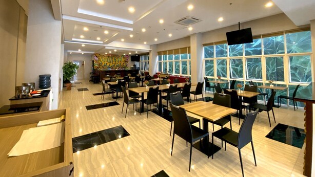 A spacious restaurant with multiple tables and chairs, a counter with a colorful mural, and large windows offering a view. - Brothers Inn Babarsari Yogyakarta (Depok)