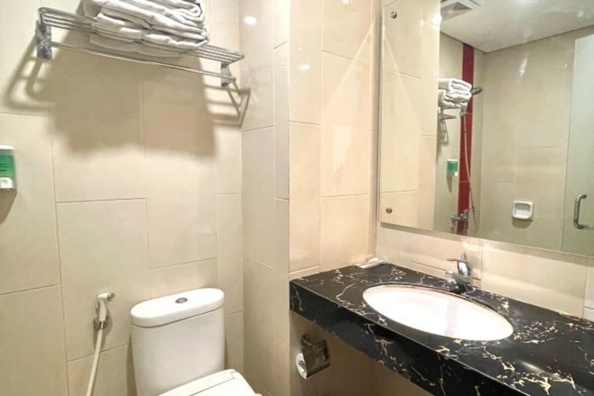 A bathroom with a toilet, a sink with a marble countertop, a towel rack, and a mirror.
