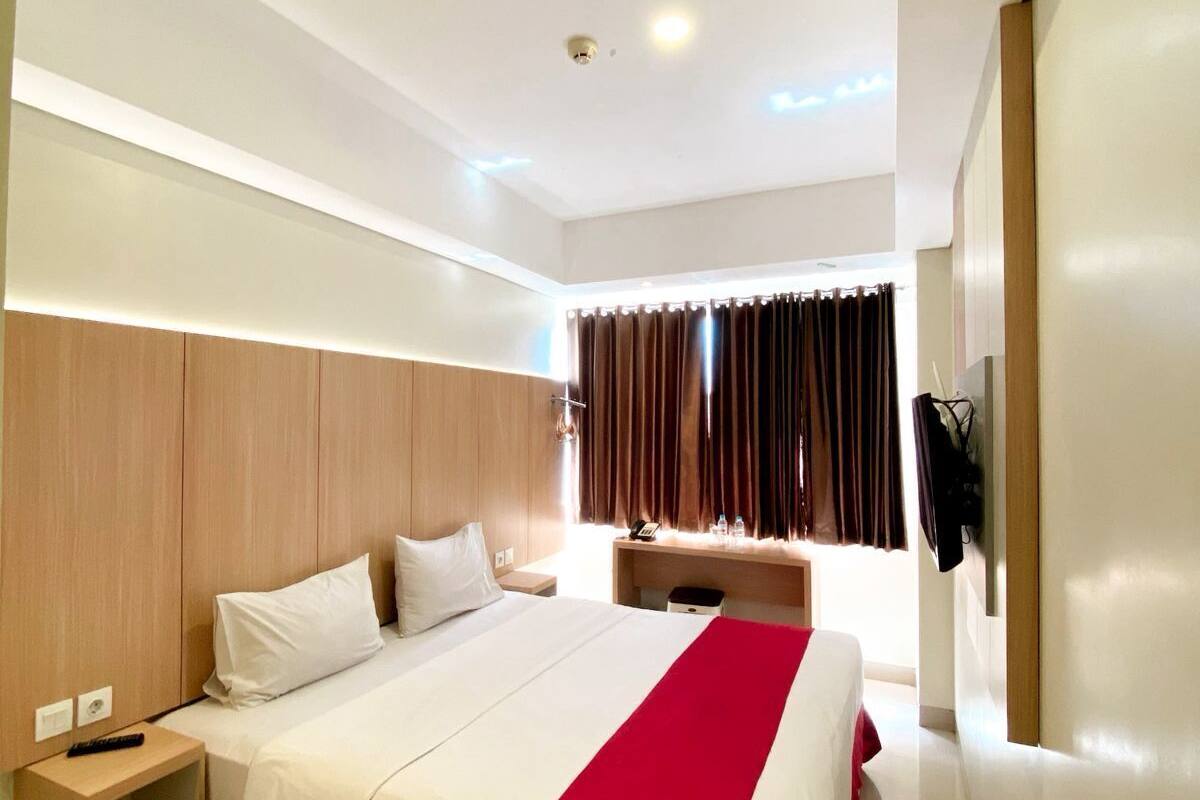 Ein modernes Hotelzimmer mit einem großen Bett, einem Holzkopfstück, Nachttischen und einem Schreibtisch mit Stuhl.