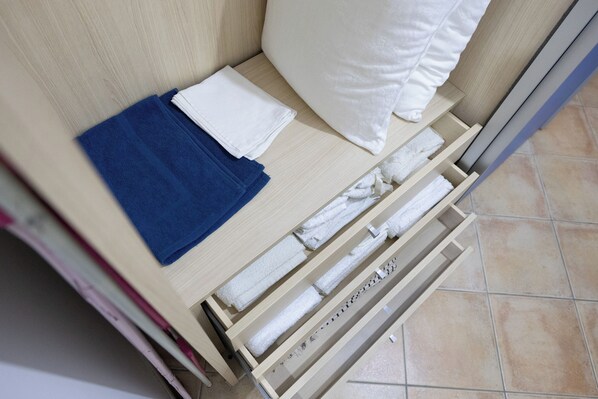 A wooden bed frame with a mattress, pillows, and neatly folded towels. - La Casetta del Porticciolo (Pisticci)