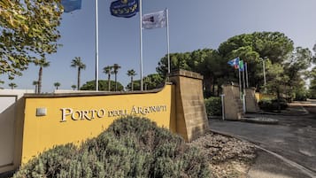 A yellow wall with the text "Porto degli Argonauti" and multiple flags, including the European Union flag.