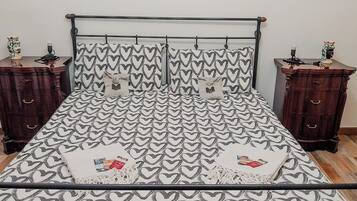 Una cama con una colcha estampada de corazones, flanqueada por dos mesitas de noche con adornos.