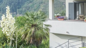 A modern house with a red-tiled roof, a balcony with outdoor seating, and a lush garden. - Villa in Vigna Apartment (San Mango sul Calore)