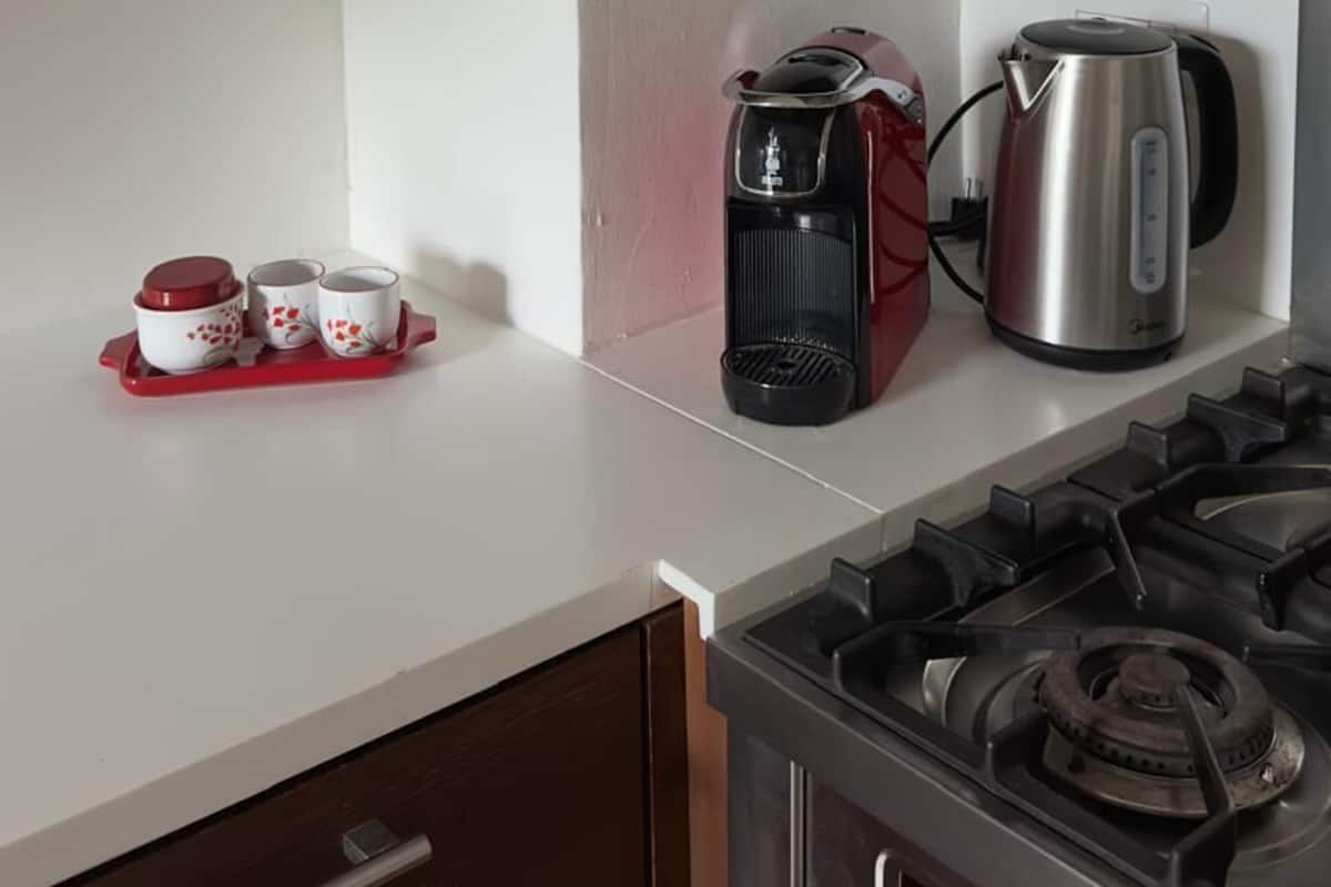 A kitchen with a stove, a coffee maker, and a kettle on the counter.