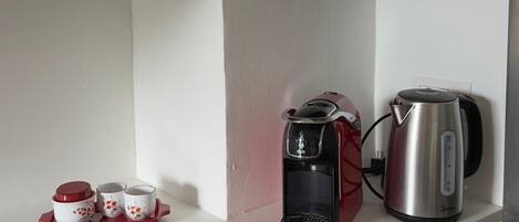 A kitchen with a stove, a coffee maker, and a kettle on the counter.