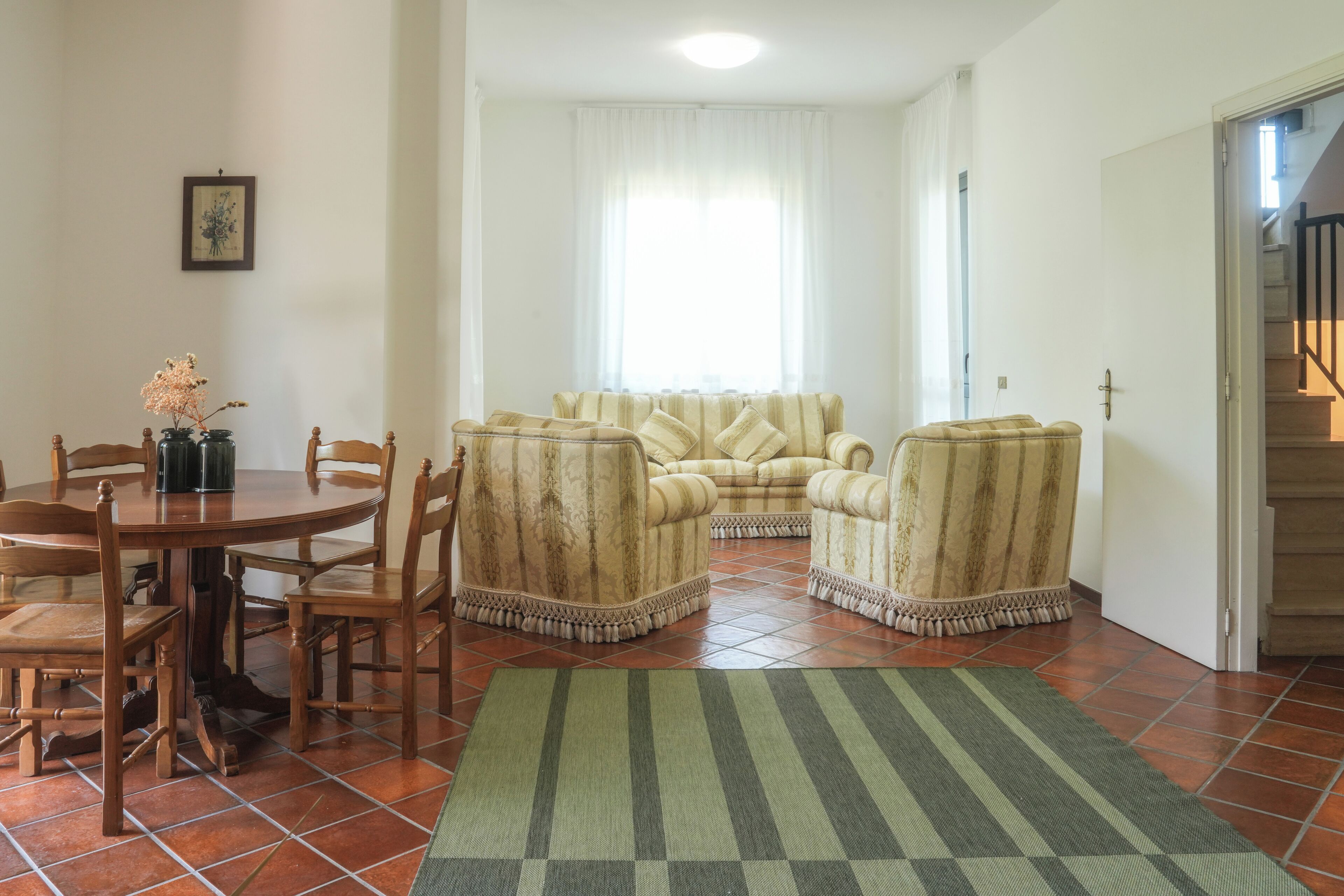 A living room with a dining table, chairs, a sofa, and a rug.