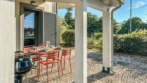 An outdoor patio with a table set for dining, a grill, and a covered area with columns. - Villa in Vigna Apartment (San Mango sul Calore)