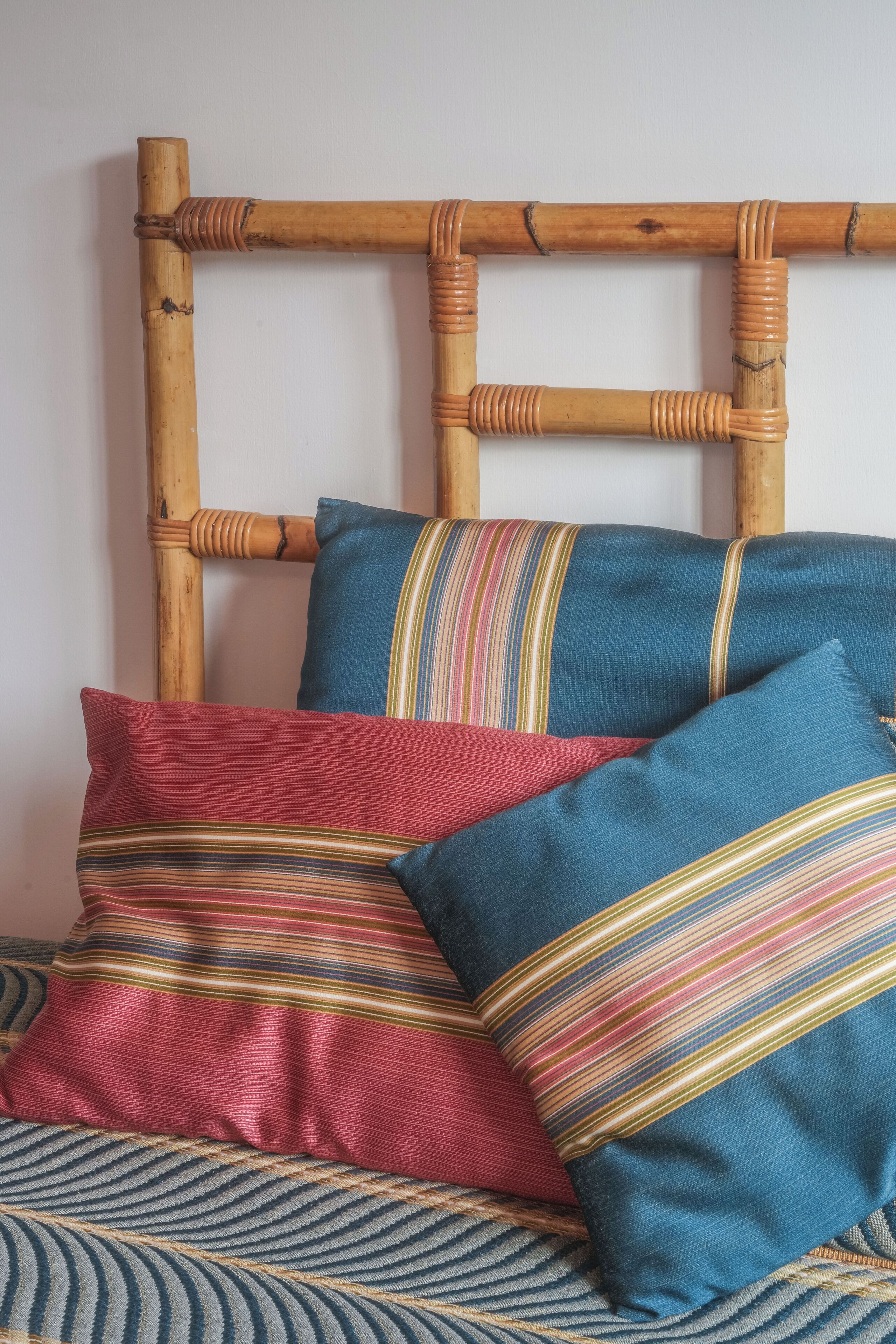 A bed with a woven headboard and striped pillows.