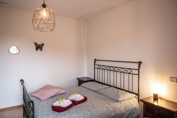 A bedroom with a bed, a nightstand, a wall-mounted light fixture, and a small window. - #914 Home - Irpinia (Nusco)