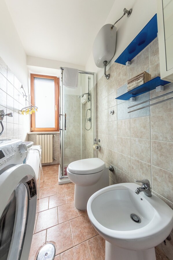 A modern bathroom with a glass shower enclosure, a toilet, a sink, and a washing machine. - #914 Home - Irpinia (Nusco)
