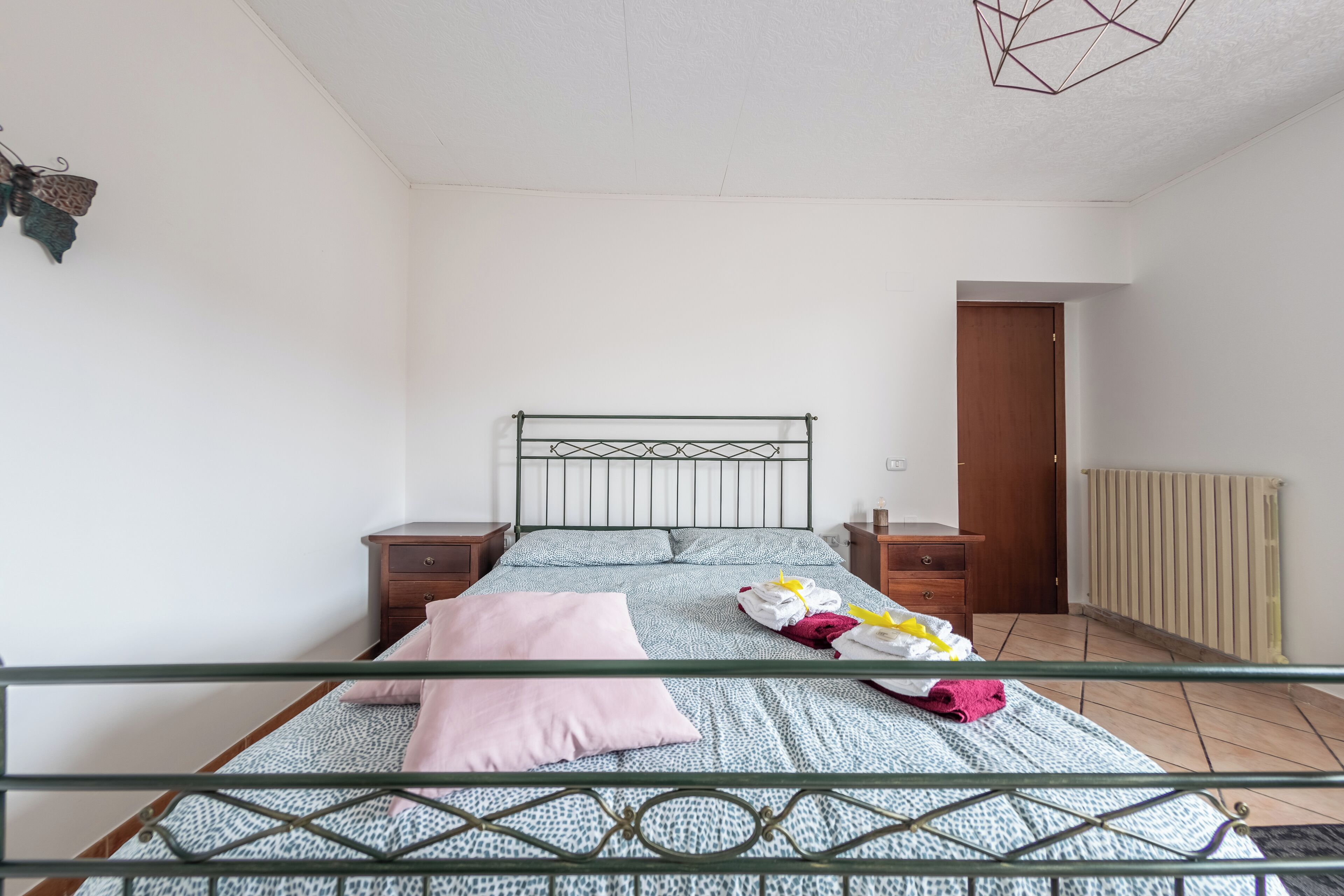 Ein Schlafzimmer mit einem Bett, zwei Nachttischen, einer Holztür und einer Heizung.