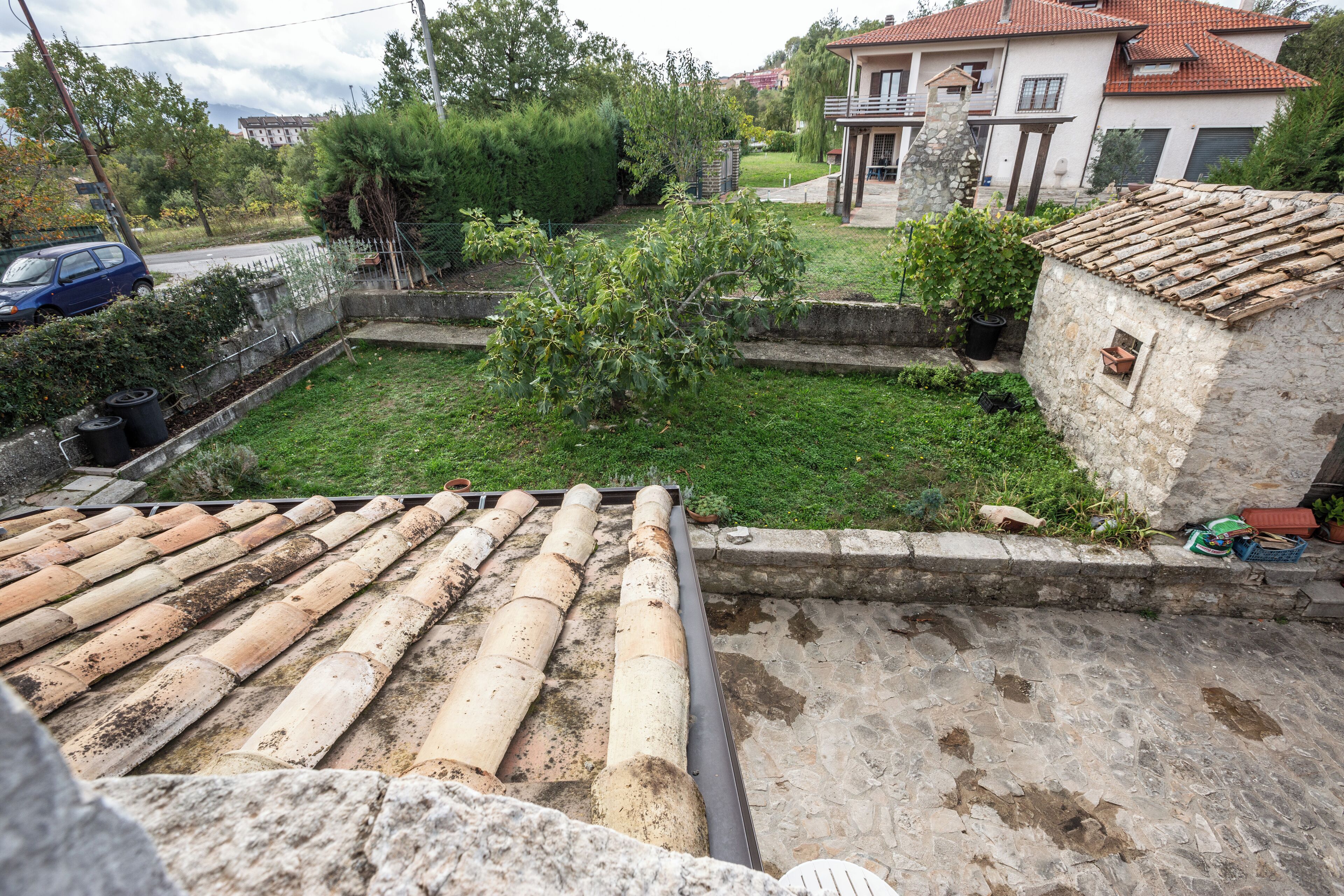 A rooftop terrace with a stone floor and a tiled roof.