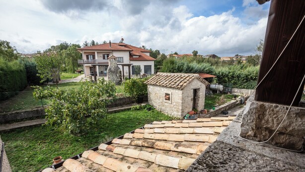 A stone staircase leading to a small stone building with a tiled roof, surrounded by greenery and a larger house in the background. - #914 Home - Irpinia (Nusco)