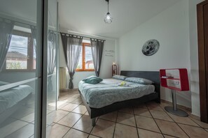 A bedroom with a bed, a bedside table, a wall clock, and a window with curtains. - #914 Home - Irpinia (Nusco)