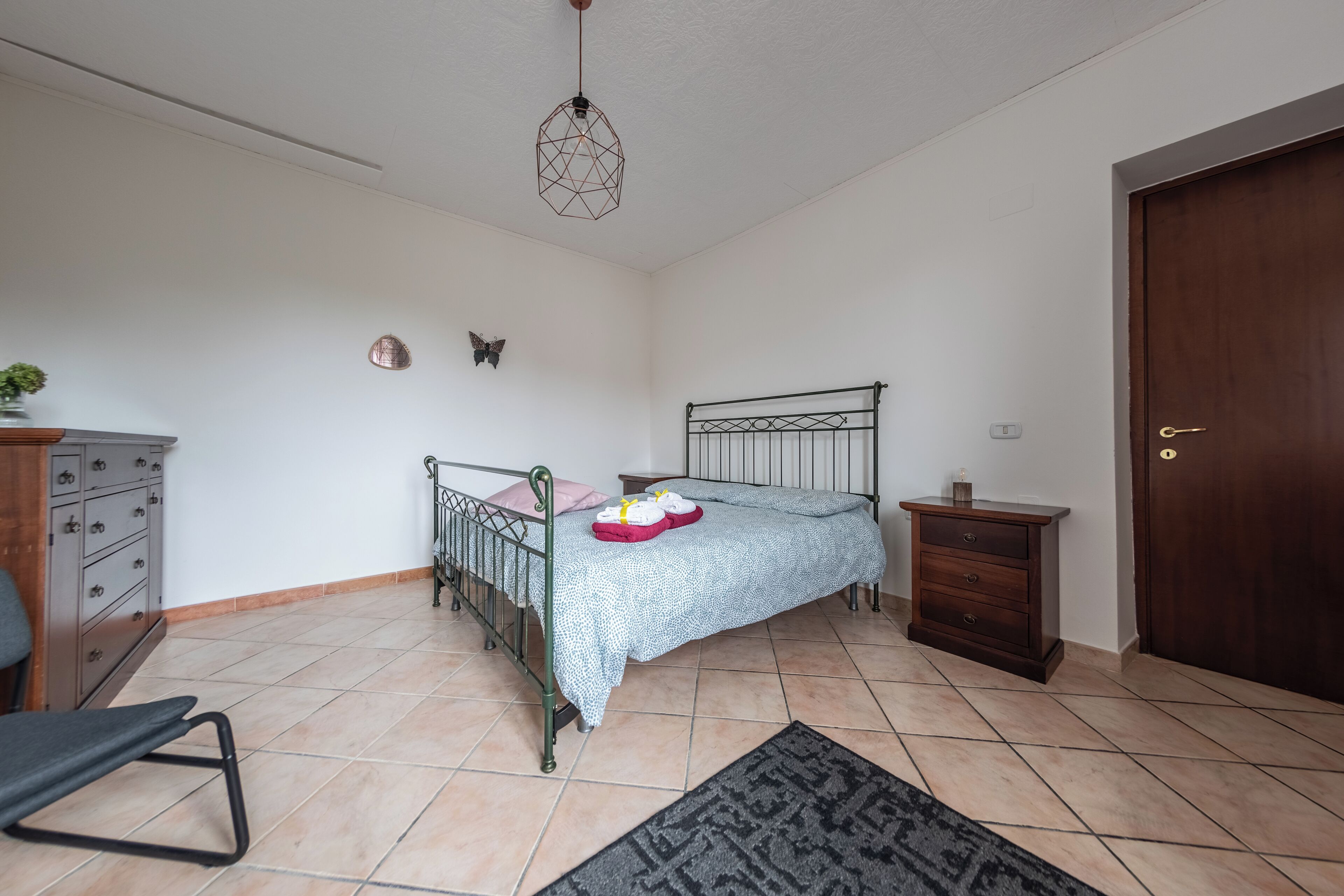 Ein Schlafzimmer mit Bett, Schminktisch, Nachttisch und einer Tür.