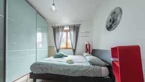 A bedroom with a bed, a red desk, a window with curtains, and a wall with a moon mural. - #914 Home - Irpinia (Nusco)