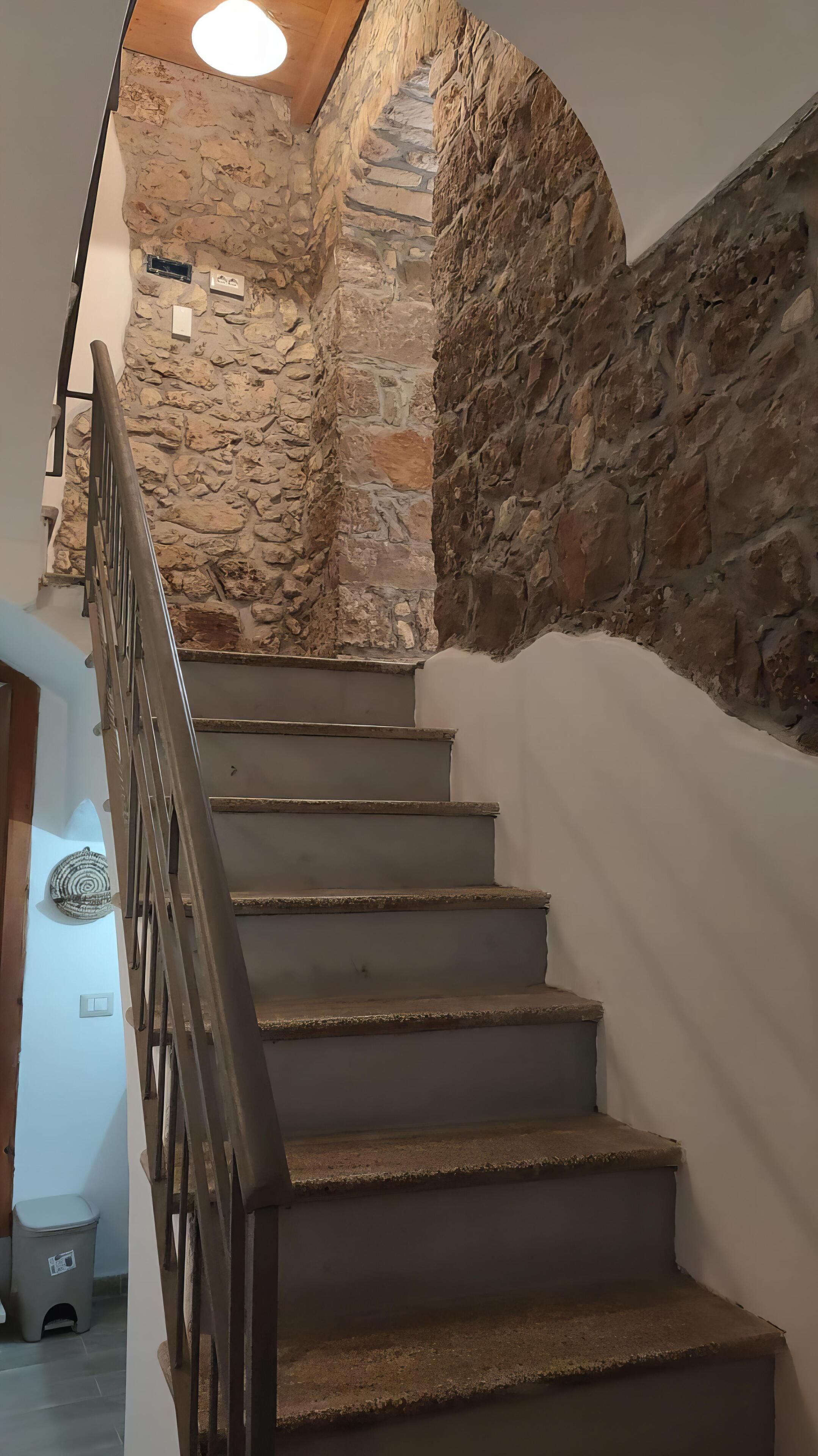 Un escalier avec des murs en pierre et une rampe en bois.