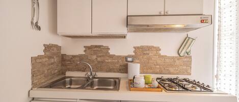 A kitchen with a sink, stove, and white cabinets.