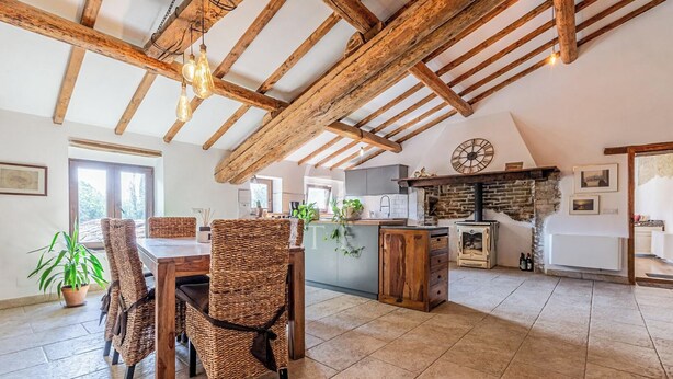 A rustic kitchen with exposed wooden beams, a stone fireplace, and a large clock on the wall. - Il Casale Di John (Umbertide)