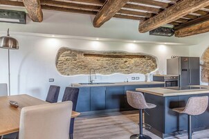 Una cocina moderna con una pared de acento de piedra, electrodomésticos integrados y una zona de bar con taburetes.