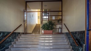 A staircase with marble steps and wooden handrails, leading to a room with a large window and a potted plant. - Billotti Central Loft - Cosenza (Cosenza)