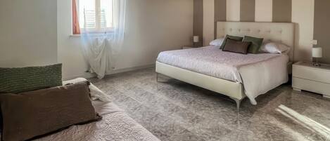 Un dormitorio con una cama, una mesita de noche, una lámpara, una ventana con cortinas y techo de madera.