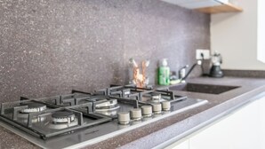 A kitchen with a gas stove, a stainless steel range hood, and a granite countertop. - Casa Vacanze Francesca (Mondolfo)